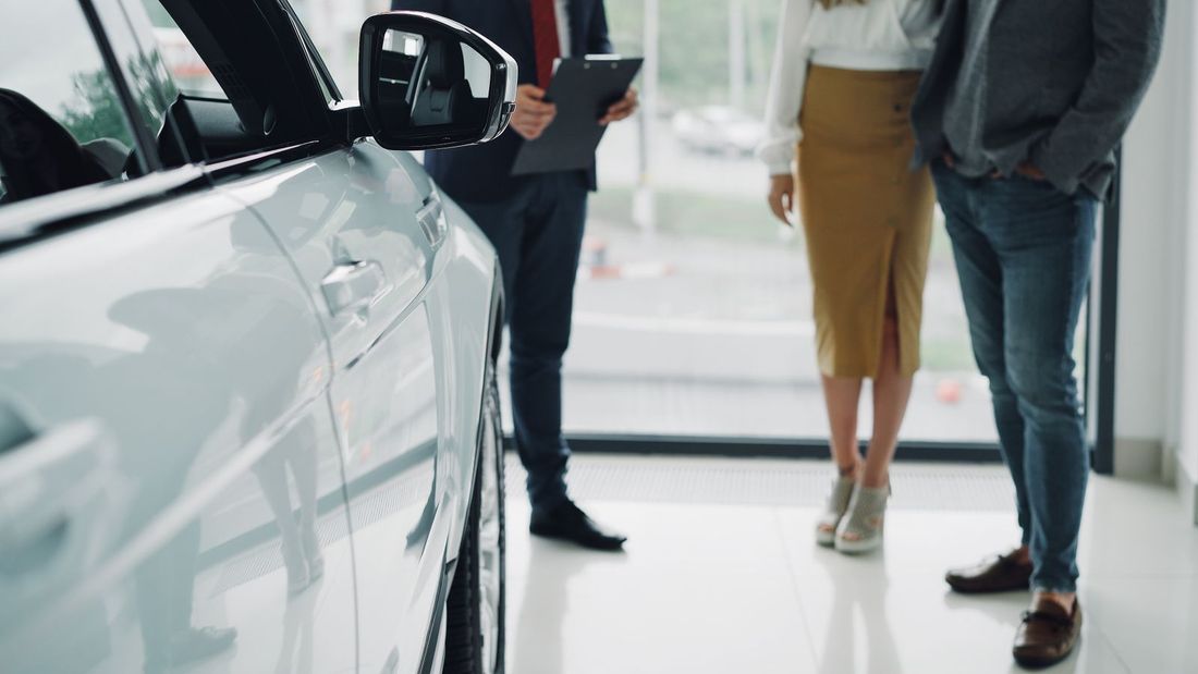 Asesor mostrando un auto a un cliente en la concesionaria